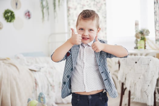 A little boy of school age raises two thumbs up, happy. photo