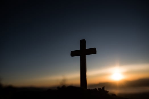 Silhouette of catholic cross and sunrise photo
