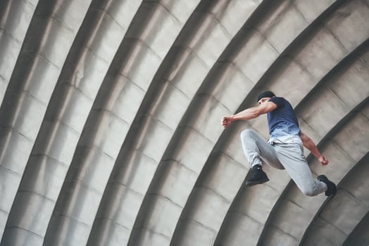 young man doing parkour jump in urban space in the city sunny spring summer day. photo