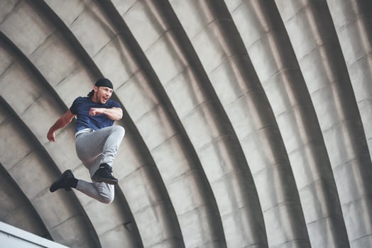 young man doing parkour jump in urban space in the city sunny spring summer day. photo