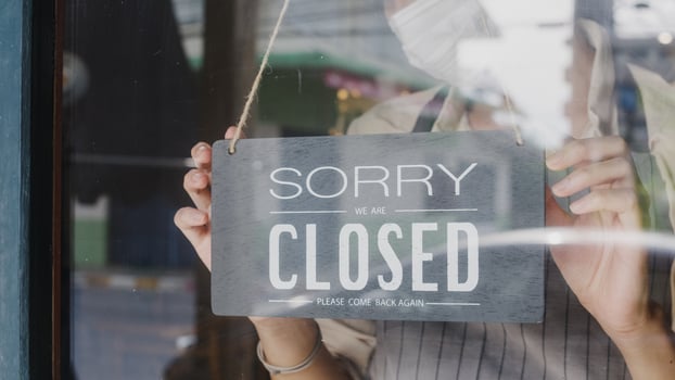 Young Asia girl wear face mask turning a sign from open to closed sign on glass door cafe after coronavirus lockdown quarantine. Owner small business, food and drink, business financial crisis concept photo