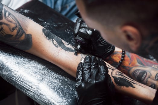 Close up tattoo machine. Master in black sterile gloves creating picture on hand with it in salon photo