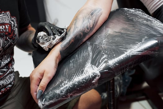 Close up tattoo machine. Master in black sterile gloves creating picture on hand with it in salon photo