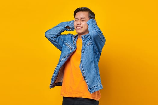 Portrait of angry Asian man covering his ears with hands photo