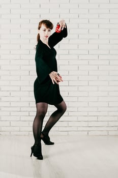 pretty woman in black dress, dancing with red castanets, white brick background photo