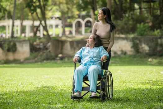Granddaughter talking with her grandmother sitting on wheelchair, cheerful concept, happy family photo