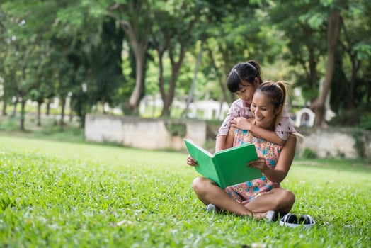 Mother and daughter reading a fairytale to her daughter in the park photo
