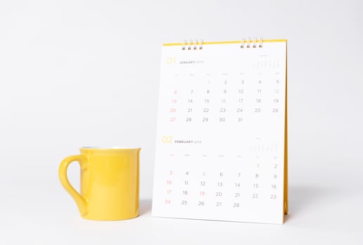 Blank yellow cap mockup and paper spiral calendar year 2019 on gray background. photo