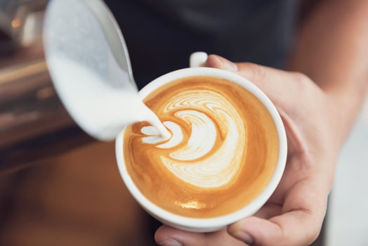 Barista making latte or Cappuccino art with frothy foam, coffee cup in cafe. photo