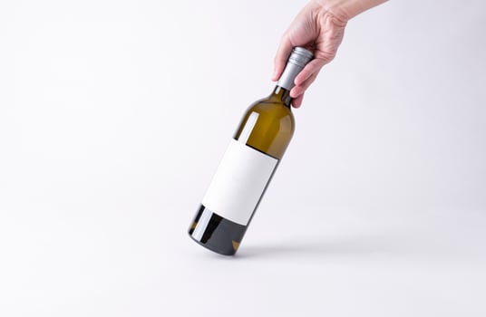 Hand holding a wine bottle for mock-up. Blank Label on a gray background. photo