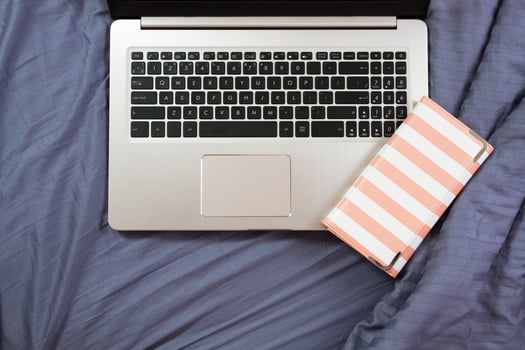 flat lay image of workplace background, laptop and clatch on bed close up photo