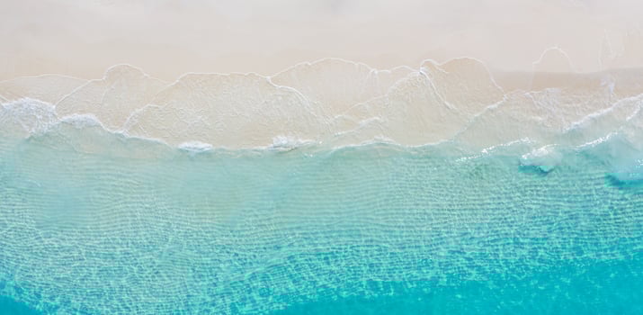 Summer seascape beautiful waves, blue sea water in sunny day. Top view from drone. Sea aerial view, amazing tropical nature background. Beautiful bright sea with waves splashing and beach sand concept photo