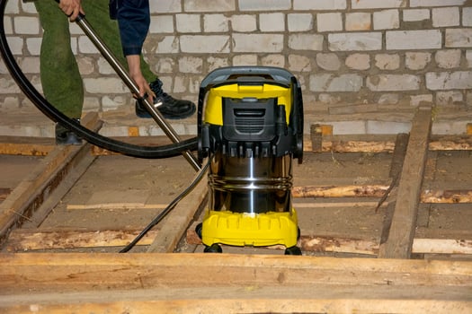 Construction vacuum cleaner. A man clean the surface from dust and debris with a powerful vacuum cleaner at a construction site. photo