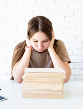 Depressed schoolgirl with a pile of books photo