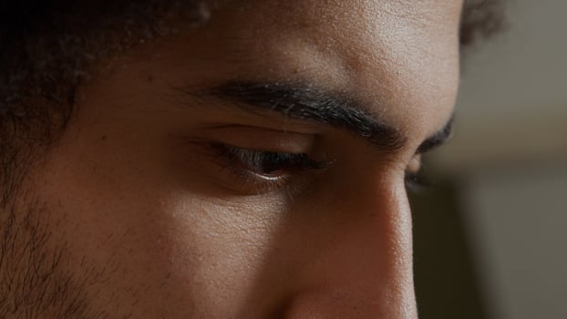Extreme close up of face of young Middle Eastern man, looking focused, fingers touching beard photo