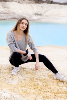 Beautiful teen woman posing at blue lake and yellow sand photo