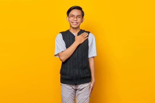 Portrait of Asian handsome young man greeting with big smile on his face on yellow background photo