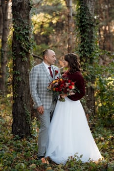 walk of the bride and groom through the autumn forest photo