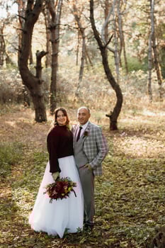 walk of the bride and groom through the autumn forest photo