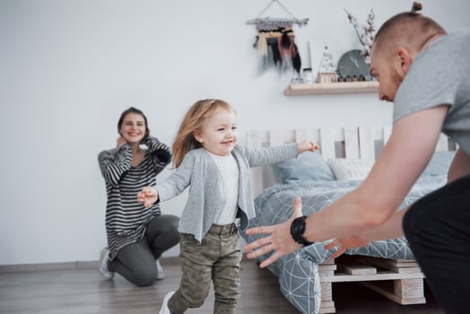 happy family is having fun at home. Mother, father and little daughter with plush toy are enjoying being together photo