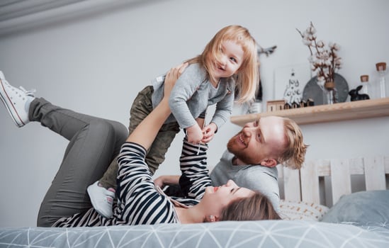 Happy family together. Mother, father and child daughter hugging in bedroom in festive day photo