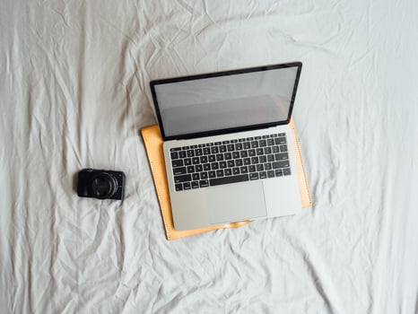 Flat lay and top view of laptop and camera on the bed. photo