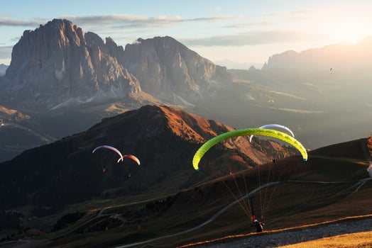 Breathtaking spectacle. Many of paragliders flying over the Seceda dolomites mountains in the evening sunrise photo