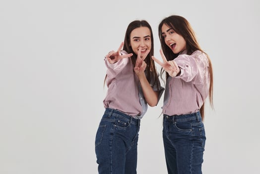Cheerful girls have fun. Two sisters twins standing and posing in the studio with white background photo