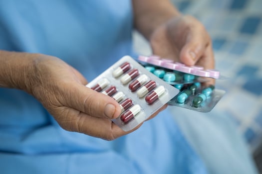 Asian senior or elderly old lady woman patient holding antibiotics capsule pills in blister packaging for treatment infection patient in hospital, Pharmacy drugstore concept. photo