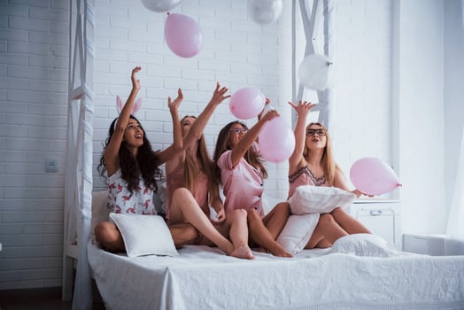 Like kids on the party. Sitting on the luxury white bed with balloons and bunny ears. Conception of bachelorette photo