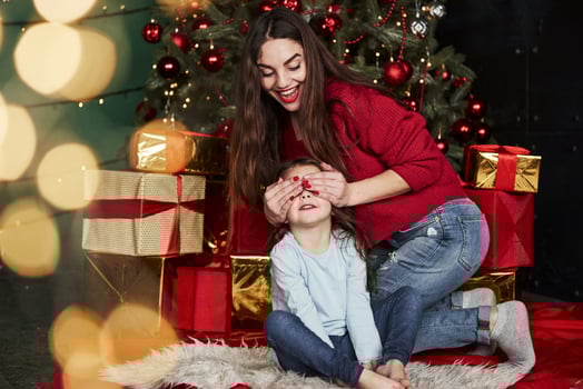 Many of the present boxes behind. Be ready for surprise. Young woman covers her daughter eyes to give the gift photo