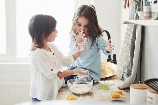 Talking during the process. Preschool friends learning how to cook with flour in the white kitchen photo
