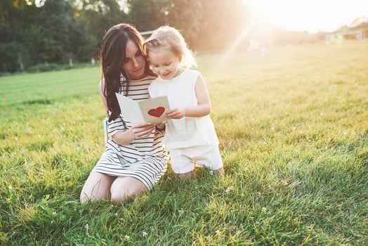 Mother and daughter sitting and reading the little book with heart on it's cover photo
