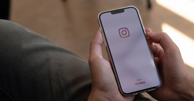 A man holds Apple iPhone 13 Pro with Instagram application on the screen at cafe. Instagram is a photo-sharing app for smartphones. photo