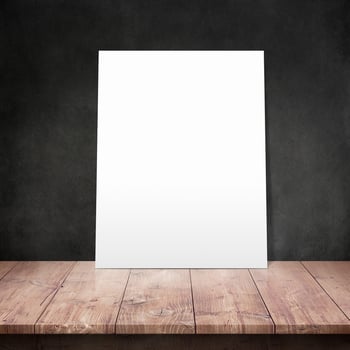 White poster on a wooden table with concrete wall background photo
