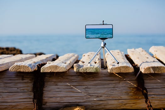 Smartphone on tripod making photo and video of sea landscape