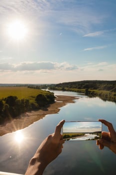 Someone using smartphone to taking photo of summer landscape
