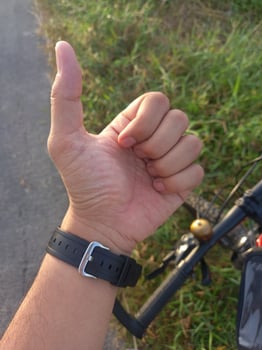 Man left hand showing thumb on grass park photo