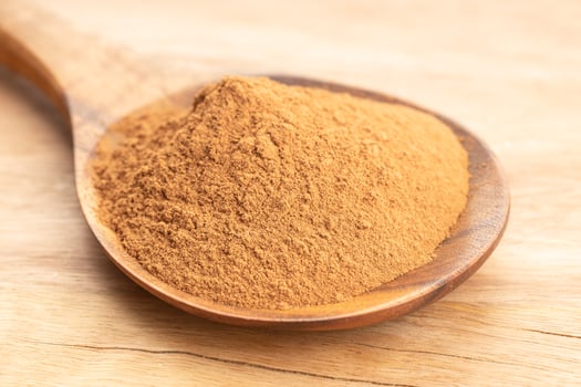 Cinnamon powder in wooden spoon on wooden table. Close up photo