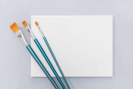 Blank White canvas and paint brushes isolated on gray background. Template, mock up photo