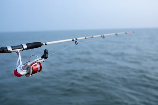 fishing rod and spinning reel and sea water background photo