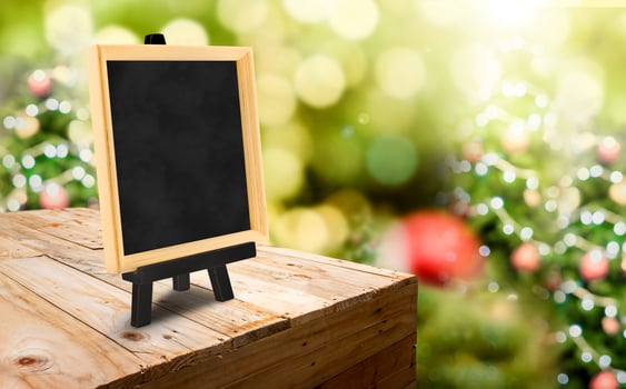 Blackboard with easel on wood table at blur Christmas tree boke photo