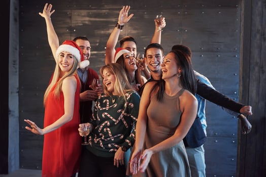 Party with friends. They love Christmas. Group of cheerful young people carrying sparklers and champagne flutes dancing in new year party and looking happy. Concepts about togetherness lifestyle photo