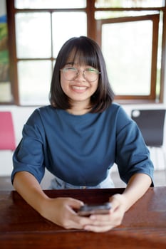 asian teenager toothy smiling with happiness and holding mobilephone in hand photo