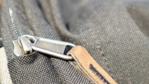 Zipper black bag backpack textile accessories. Close-up view of the clasp. Textile, metal and brown leather. photo