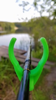 Fishing rod feeder on a stand against a lake. Close fishing on the river, fishing rod stands on a green slingshot photo