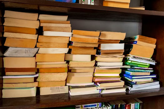 Old yellowed books stacked on the shelf in bookcase, library. photo