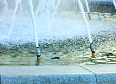 Powerful jets of water in a city fountain made of polished granite burst from metal nozzles. photo