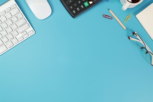 workspace business desk with computer, glasses, calculator, banknote and pencil on blue background photo
