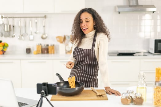 Latin woman shooting video and cooking at the kitchen photo